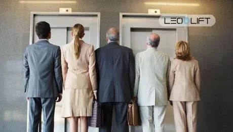 Five businesspeople in suits stand with their backs to the camera, waiting at two elevator doors; LEO LIFT logo visible above.
