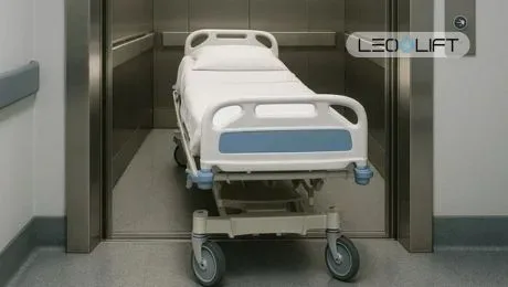 Hospital patient bed on a wheeled transport trolley inside an elevator, ready for patient transfer.