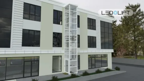 Modern three-story building with a glass-enclosed external elevator shaft in the center.