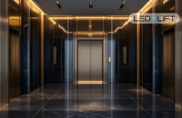 Hotel-style elevator lobby with three dark marble walls, gold lighting, and centered silver elevator doors.