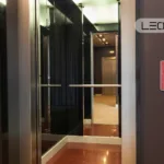 Open elevator doors with mirrored walls, chrome handrails, and LEOLIFT branding in the corner.
