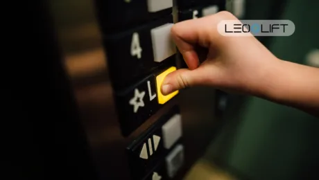 Close-up of a hand pressing a yellow elevator call button on a dark control panel