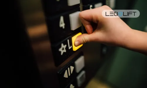 Close-up of a hand pressing a yellow elevator call button on a dark control panel