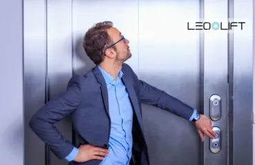 Man in a blue suit reaches for an elevator door handle, with the LEO LIFT logo in the top-right corner.